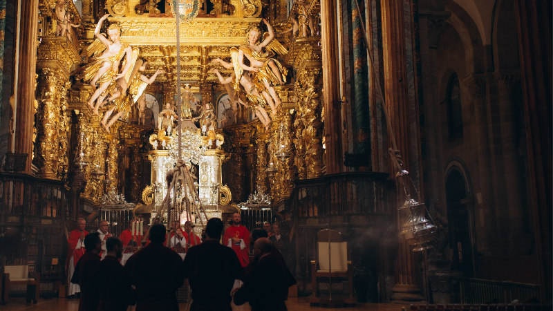 Il Botafumeiro in azione nella Cattedrale di Santiago, durante una solenne celebrazione liturgica con i turibolanti in primo piano.