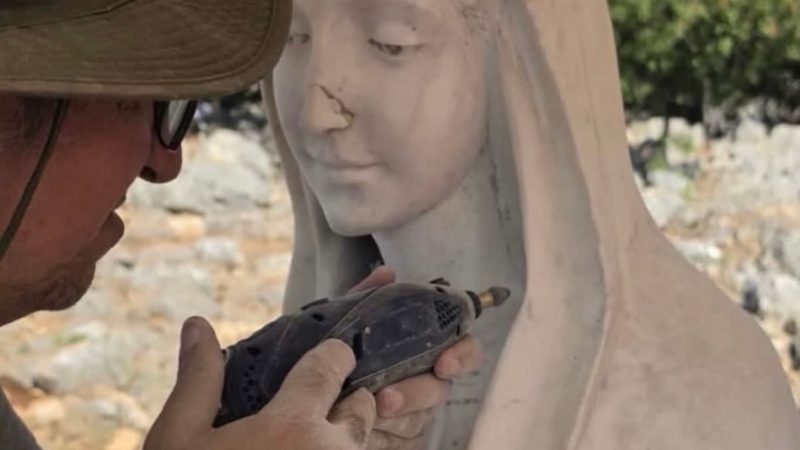 Le mani di un restauratore lavorano sul volto in marmo della statua della Madonna di Medjugorje