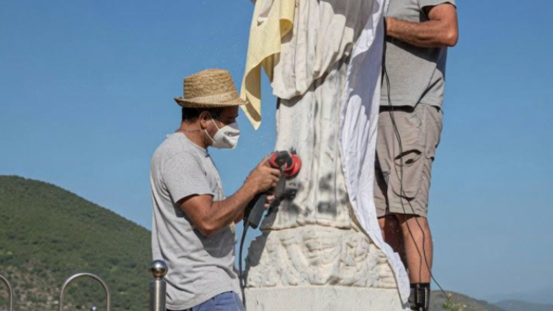 Uomini di Bijakovići puliscono la statua della Madonna di Medjugorje coperta dai teli, il giorno stesso del vandalismo